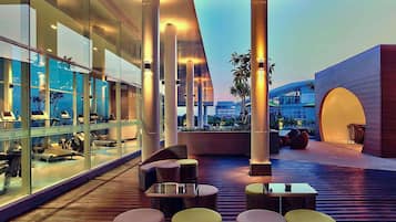Un espacio moderno al aire libre con mobiliario de mimbre y paredes de vidrio.