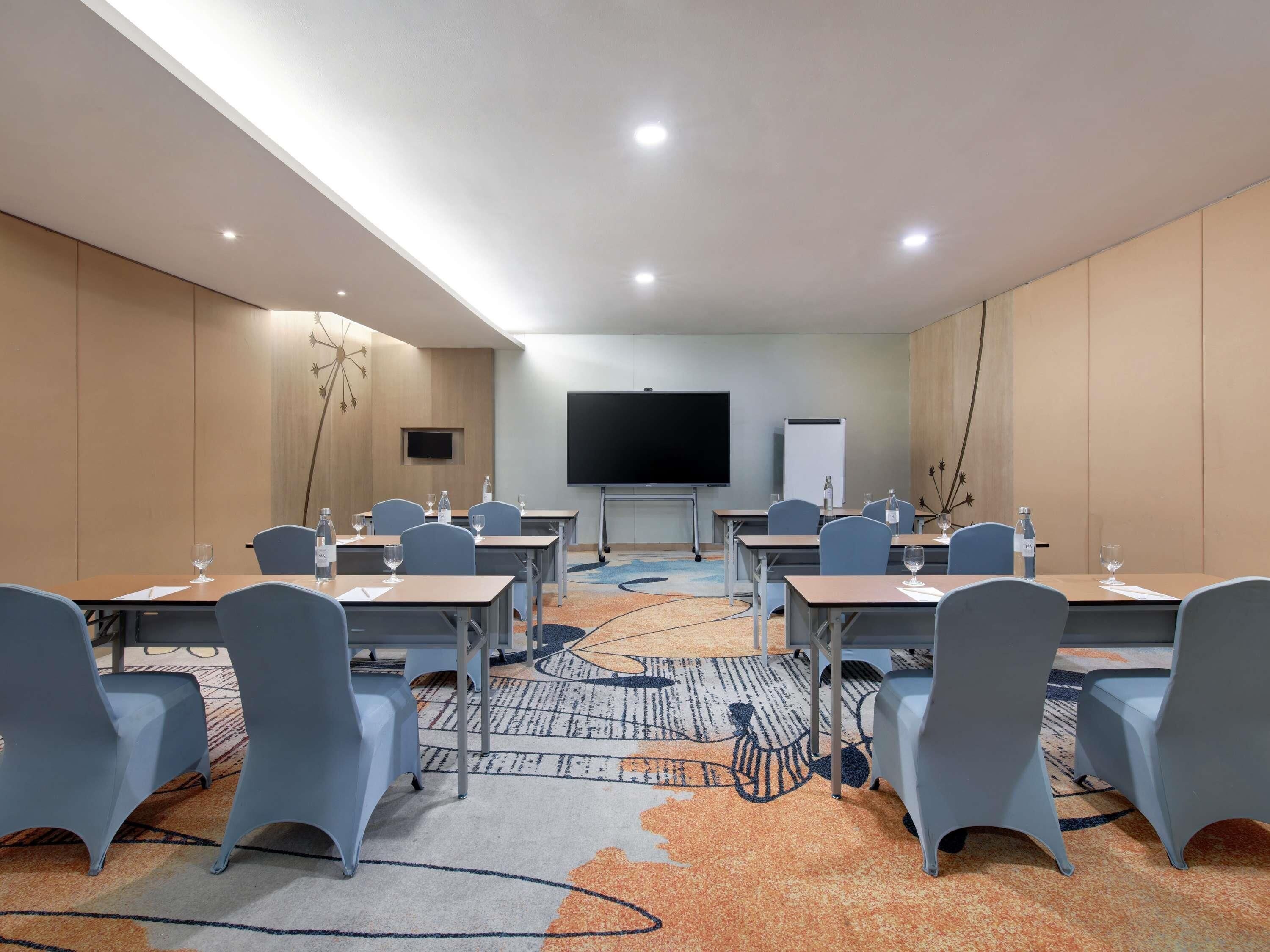 A conference room with tables, chairs, a projector screen, and a whiteboard.