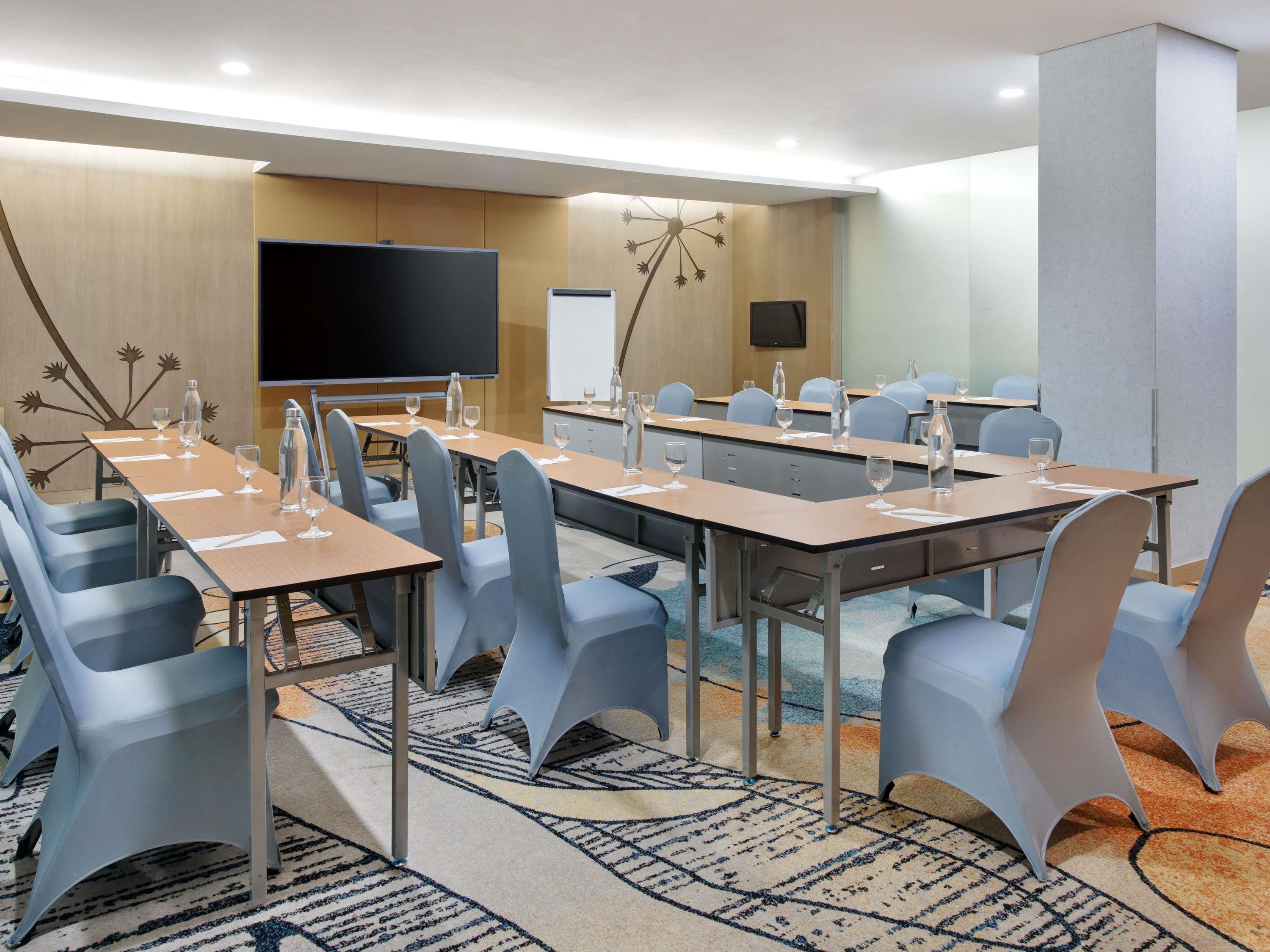 A conference room with tables, chairs, a projector screen, and a whiteboard.