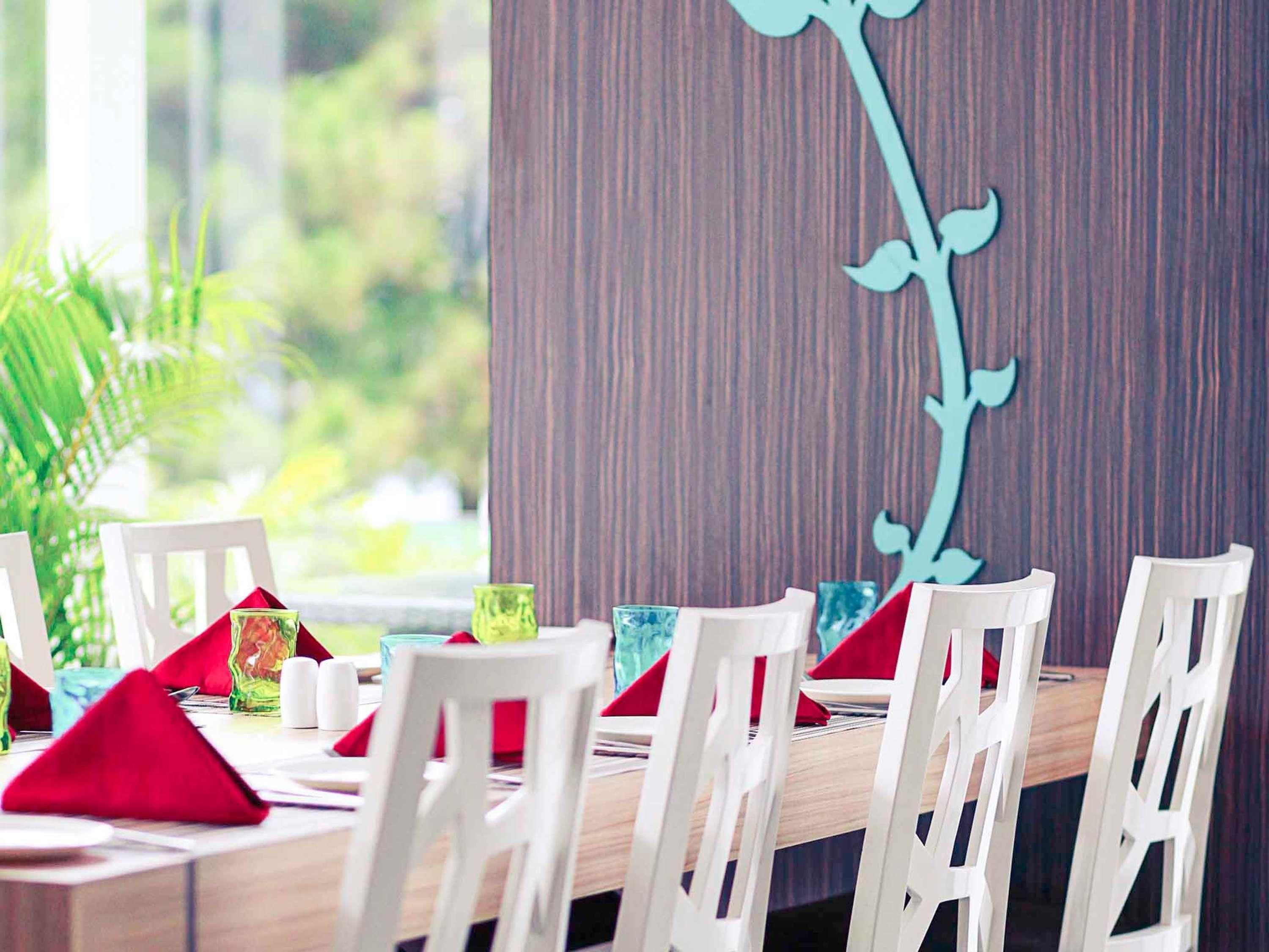 A dining area with white chairs, red napkins, and a wooden table.