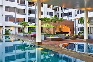 Um hotel moderno com piscina no terraço, áreas de estar ao ar livre e um jardim bem cuidado.