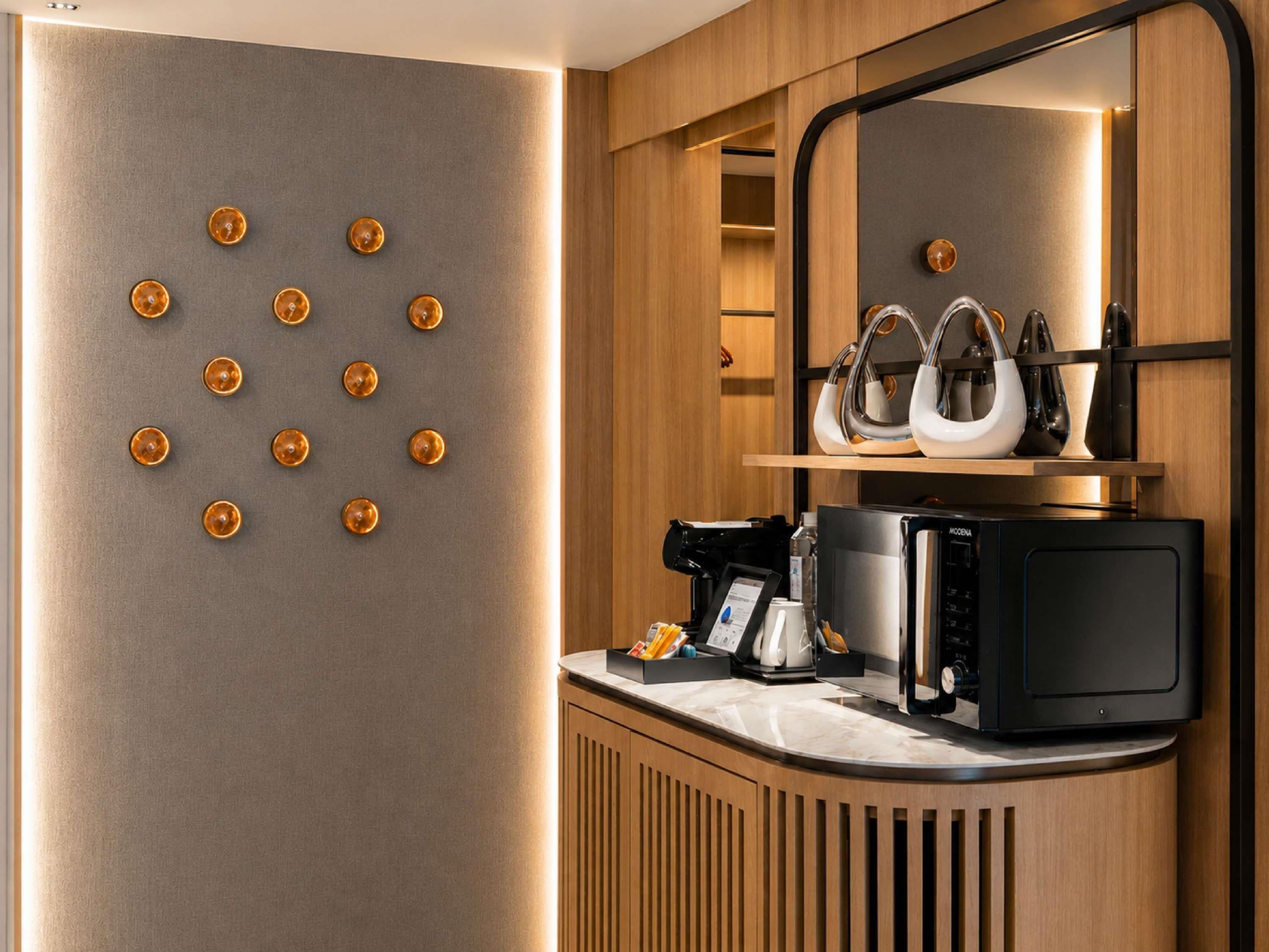 A modern kitchen with a coffee machine, microwave, and utensils on the counter.