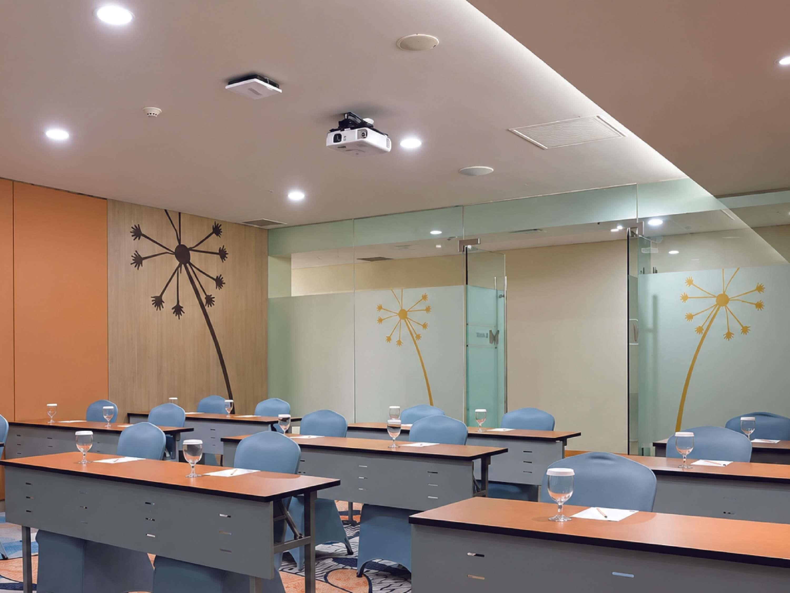 A conference room with tables, chairs, and a projector.