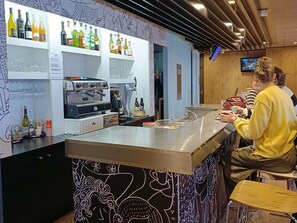 A bar area with a coffee machine, shelves of bottles, and glasses. - ibis Aurillac (Aurillac)