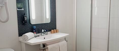A modern bathroom with a white toilet, a sink with a mirror, and a glass-enclosed shower.