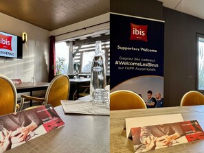 A hotel reception area with a large sign welcoming supporters, a television displaying the hotel's name, and brochures on the table. - ibis Aurillac (Aurillac)