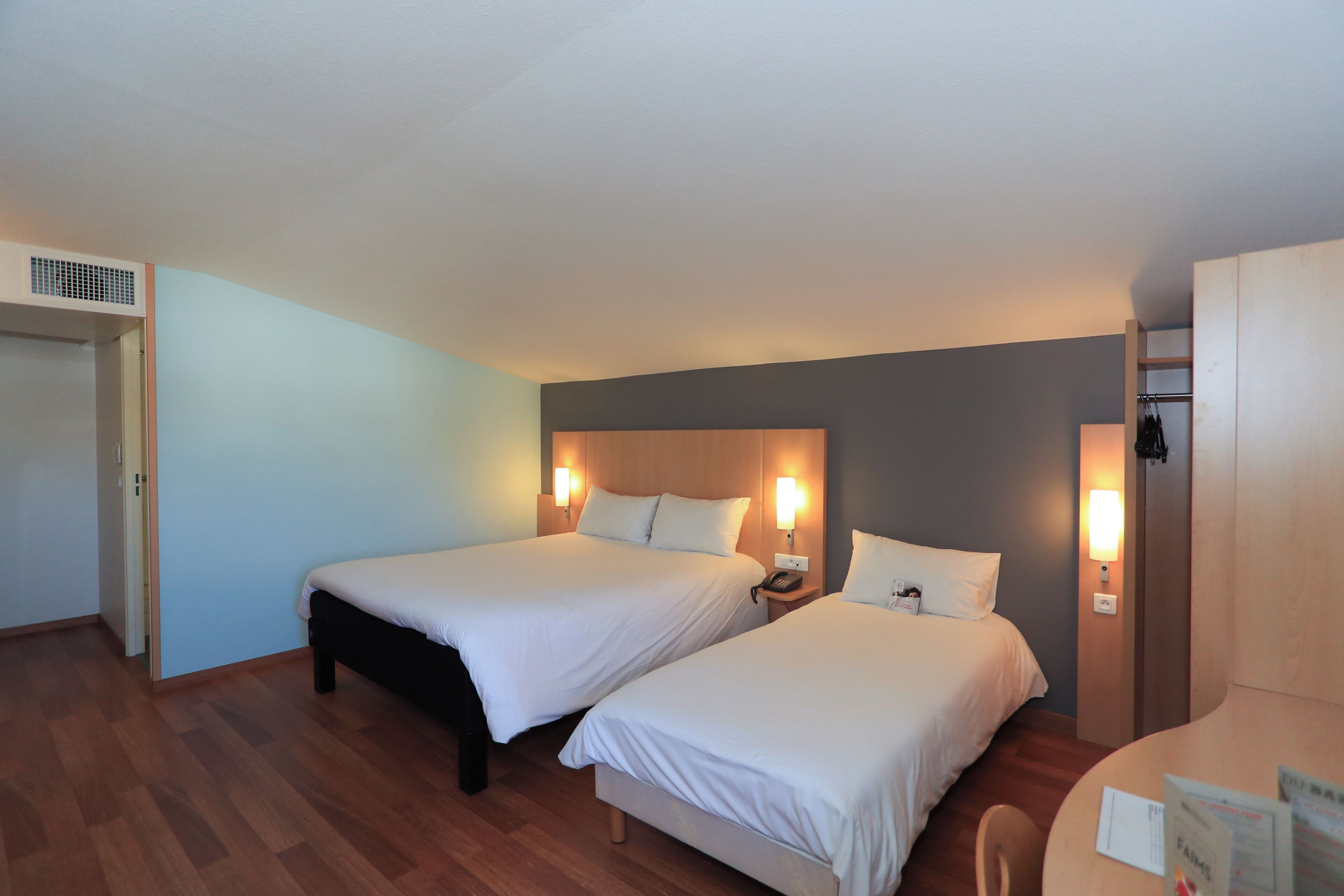 Une chambre d’hôtel avec deux lits, un bureau et une chaise.