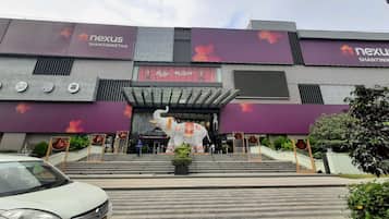 A modern building with a large entrance, a statue, and a car parked in front.