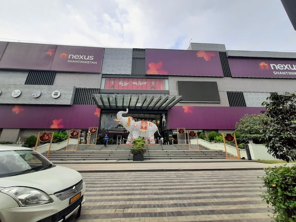 Un edificio moderno con una entrada amplia, una estatua y un automóvil estacionado frente a él.