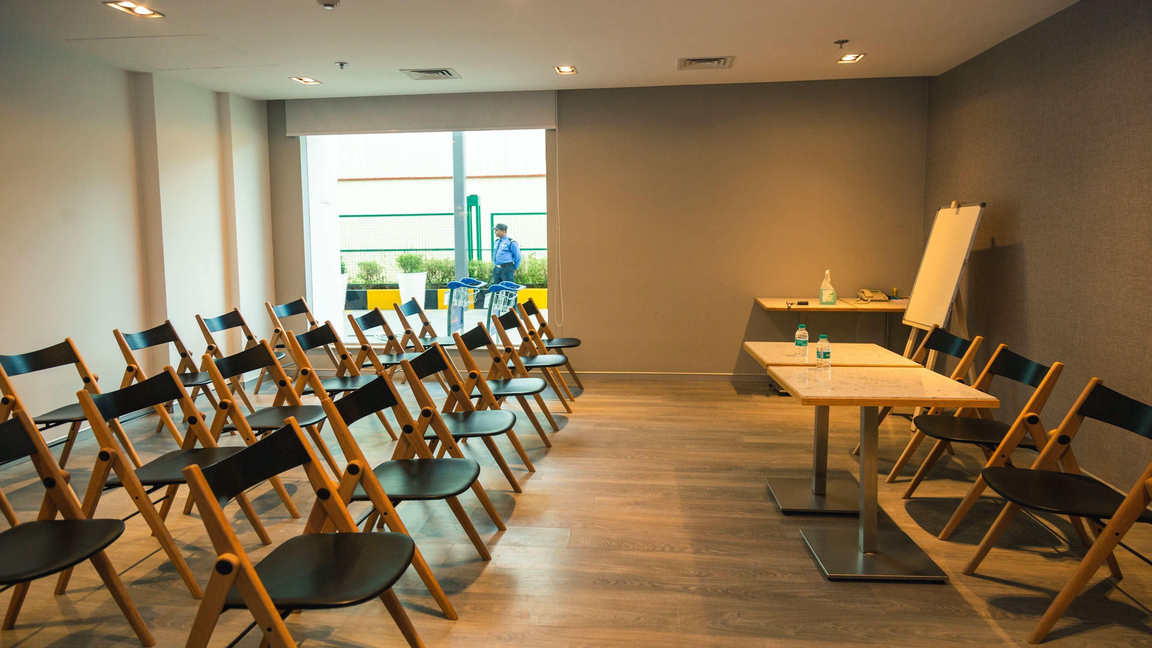 A conference room with rows of chairs, a table, and a whiteboard.