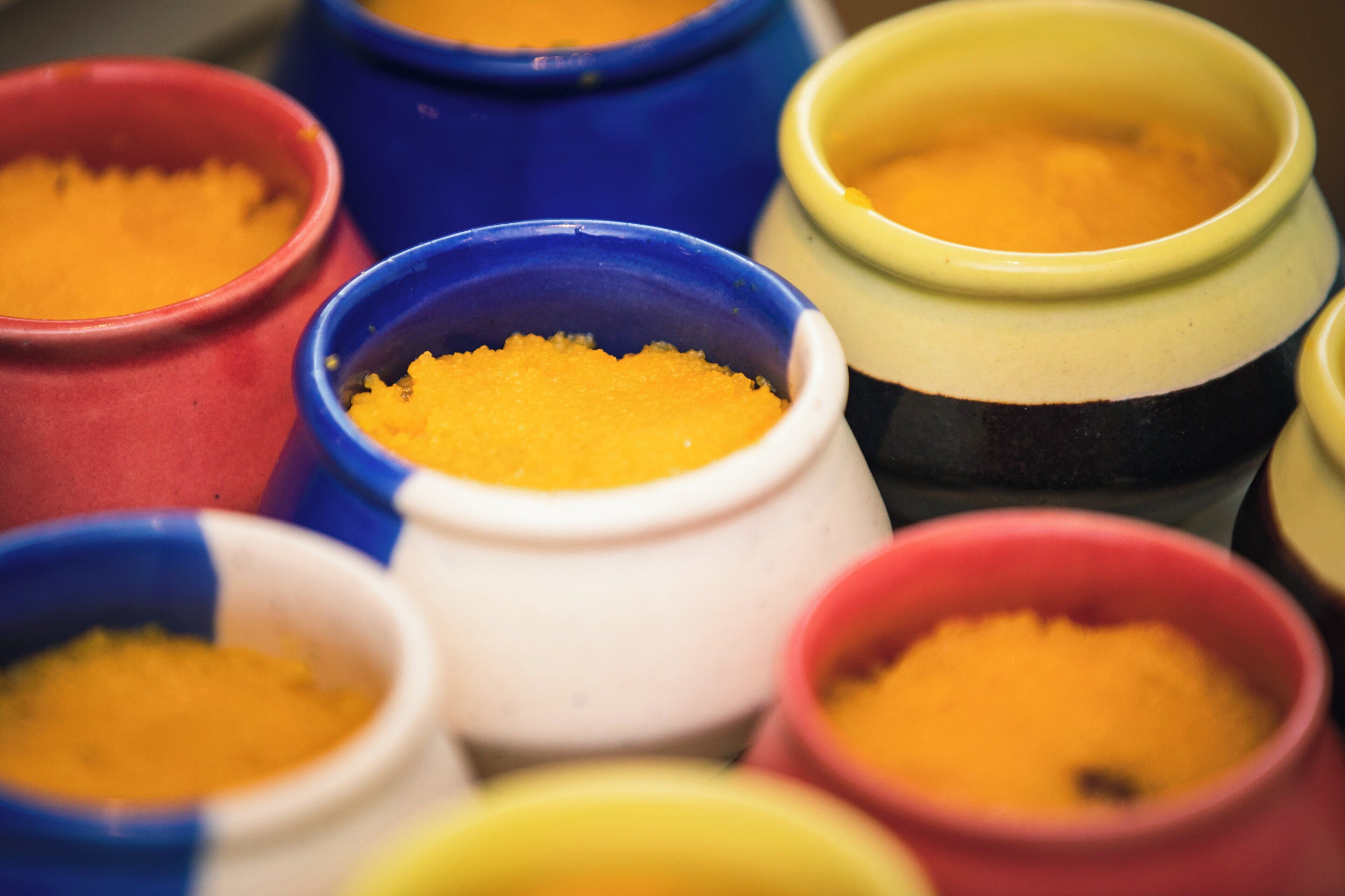 A collection of colorful ceramic containers with a granular substance inside.