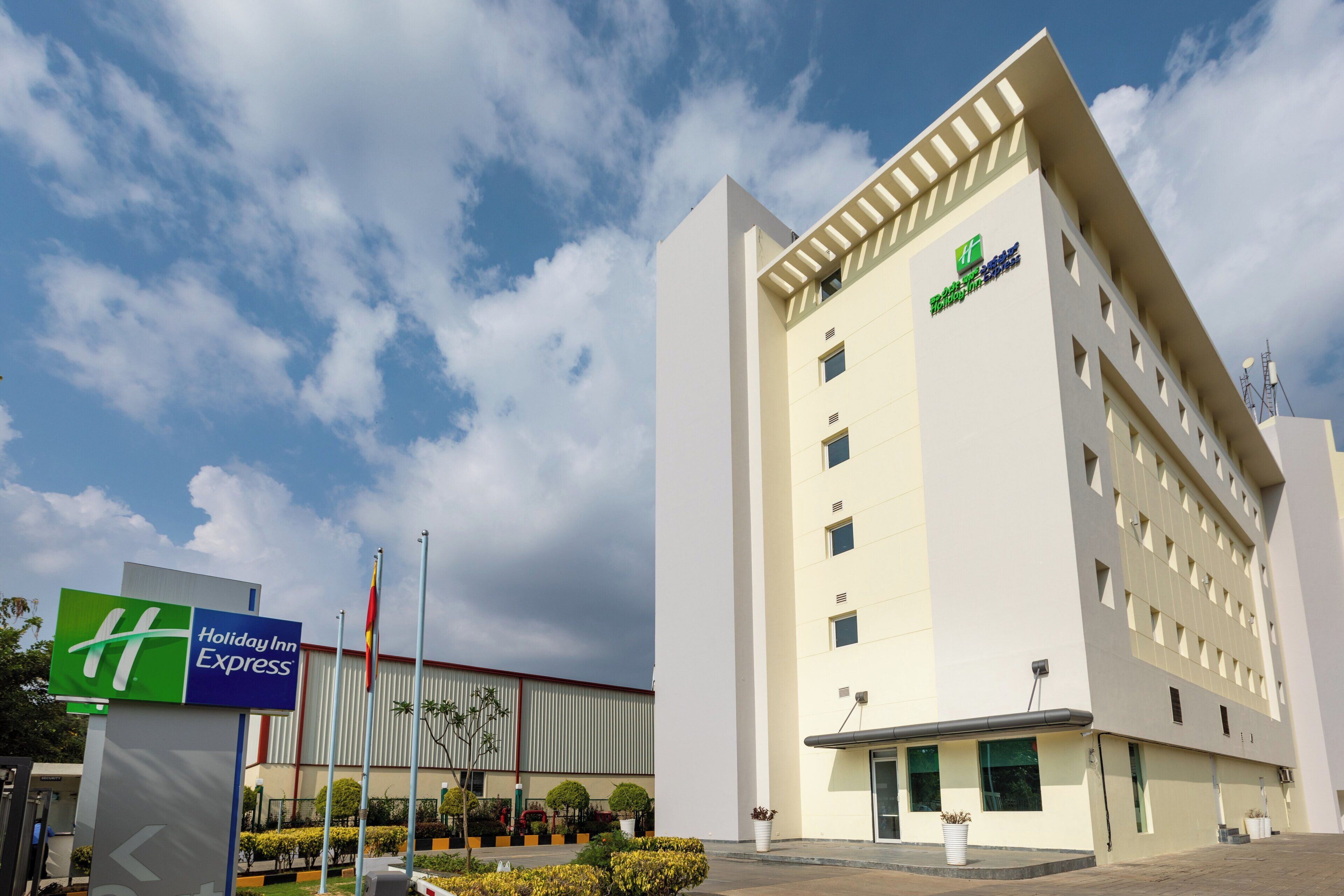 Um hotel Holiday Inn Express com design moderno, destacando uma entrada imponente e um céu claro.
