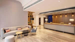 A modern lobby with a reception desk, a sofa, a coffee table, and a chair. - Holiday Inn Express Bengaluru Whitefield Itpl by IHG (Bengaluru)