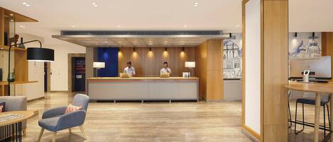 A hotel reception area with a reception desk, two receptionists, a blue armchair, a round table, and a bar area with a TV.