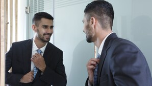 A man in a suit adjusting his tie in front of a mirror. - Holiday Inn Express Bengaluru Whitefield Itpl by IHG (Bengaluru)