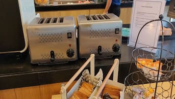 Two toasters with 4PCS slots, a metal rack with bread, and a sign about bread toasting method.