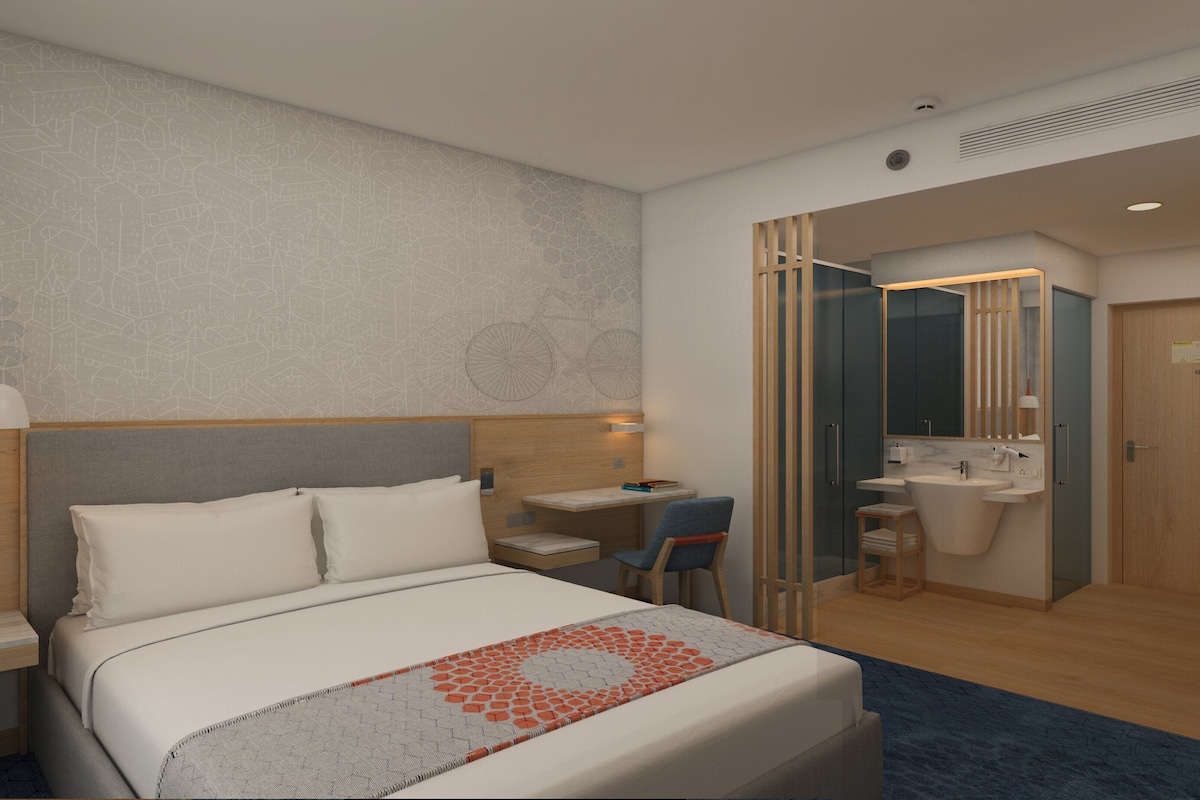 Habitación de hotel con cama, escritorio, silla, baño y armario.