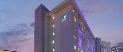 Un edificio moderno con insegna Holiday Inn Express, numerose finestre e tetto piano.
