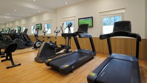 A gym with various exercise equipment, including treadmills and stationary bikes, and a television screen displaying a sports event. - Holiday Inn Express Bengaluru Whitefield Itpl by IHG (Bengaluru)