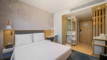 Een hotelkamer met een groot bed, een bureau, een stoel, een kledingkast en een badkamer.