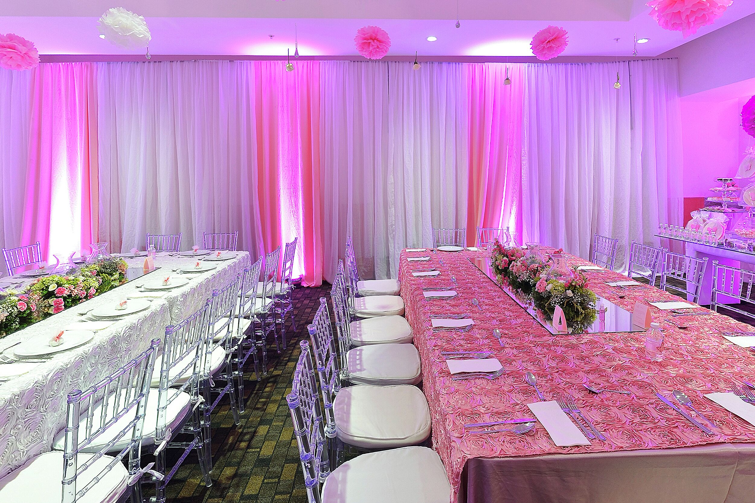 Une salle de banquet avec de longues tables, des chaises et une composition florale.