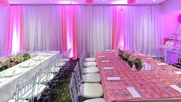 Une salle de banquet avec de longues tables, des chaises et une composition florale.