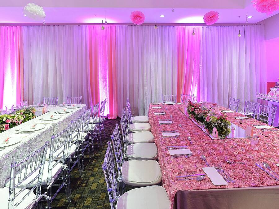 Une salle de banquet avec de longues tables, des chaises et une composition florale.