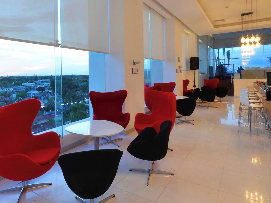A modern interior with red and black chairs, a white table, and a view of a cityscape through large windows.