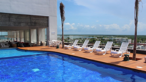 A rooftop pool with white lounge chairs and a view of the city. - Fiesta Inn Chetumal Hotel (Chetumal)