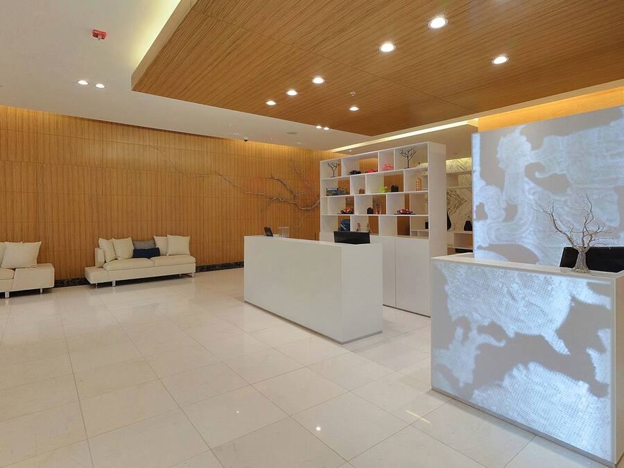 A modern reception area with a wooden ceiling, white reception desk, and a seating area with sofas.