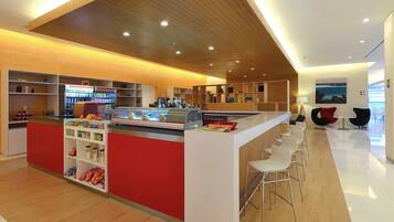 Zona de bar moderna con mostrador, asientos y máquina expendedora.
