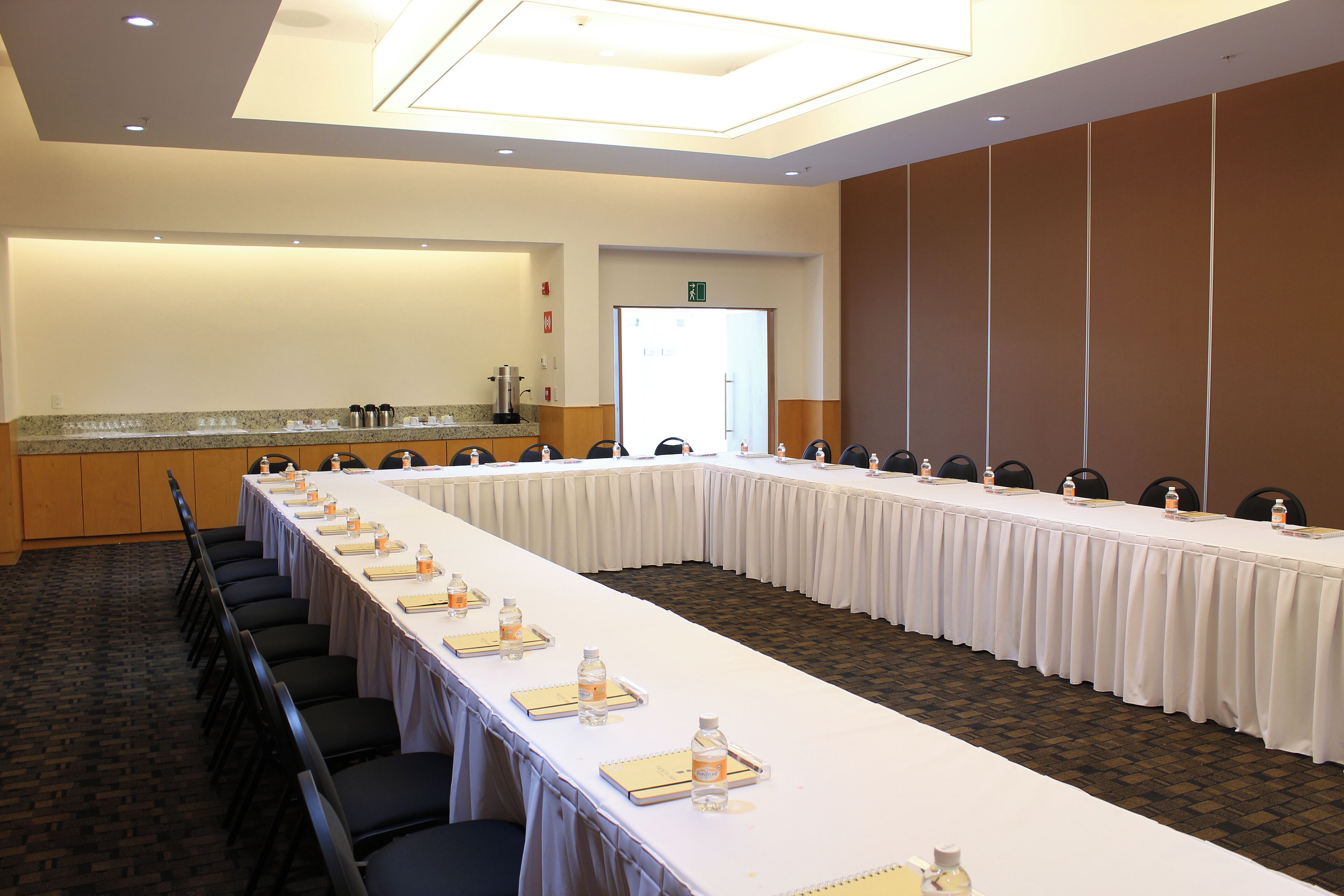 A conference room with a long table, chairs, and a kitchenette area.