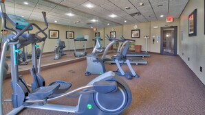 A gym with various exercise machines, a carpeted floor, and a mirrored wall. - Holiday Inn Express Hotel & Suites Lubbock South by IHG (Lubbock)