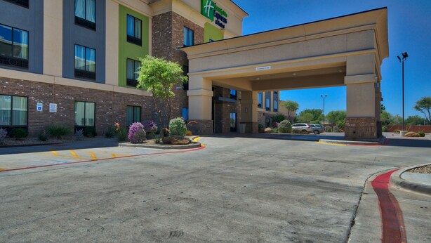 A hotel with a modern design, featuring a prominent green and beige color scheme, a covered entrance, and a landscaped area with plants. - Holiday Inn Express Hotel & Suites Lubbock South by IHG (Lubbock)