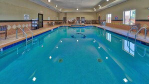A large indoor pool with a capacity sign, lounge chairs, and a lifeguard chair. - Holiday Inn Express Hotel & Suites Lubbock South by IHG (Lubbock)