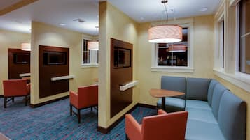A hotel lobby with seating areas, a reception desk, and a television screen.