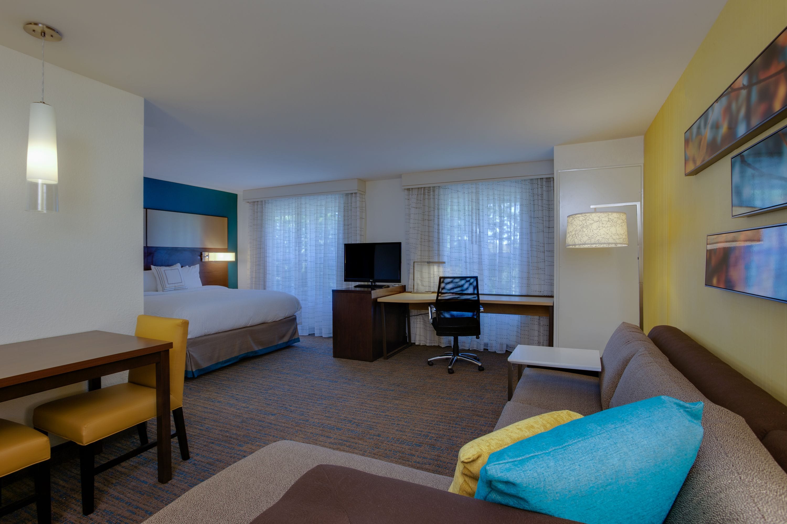 A hotel room with a bed, desk, chair, and a sofa.