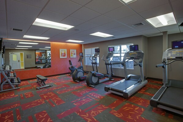 A gym with treadmills, elliptical machines, and weight benches.