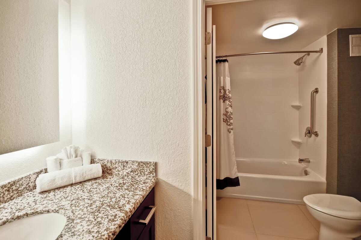 Un baño con ducha, inodoro y lavabo con toallero.