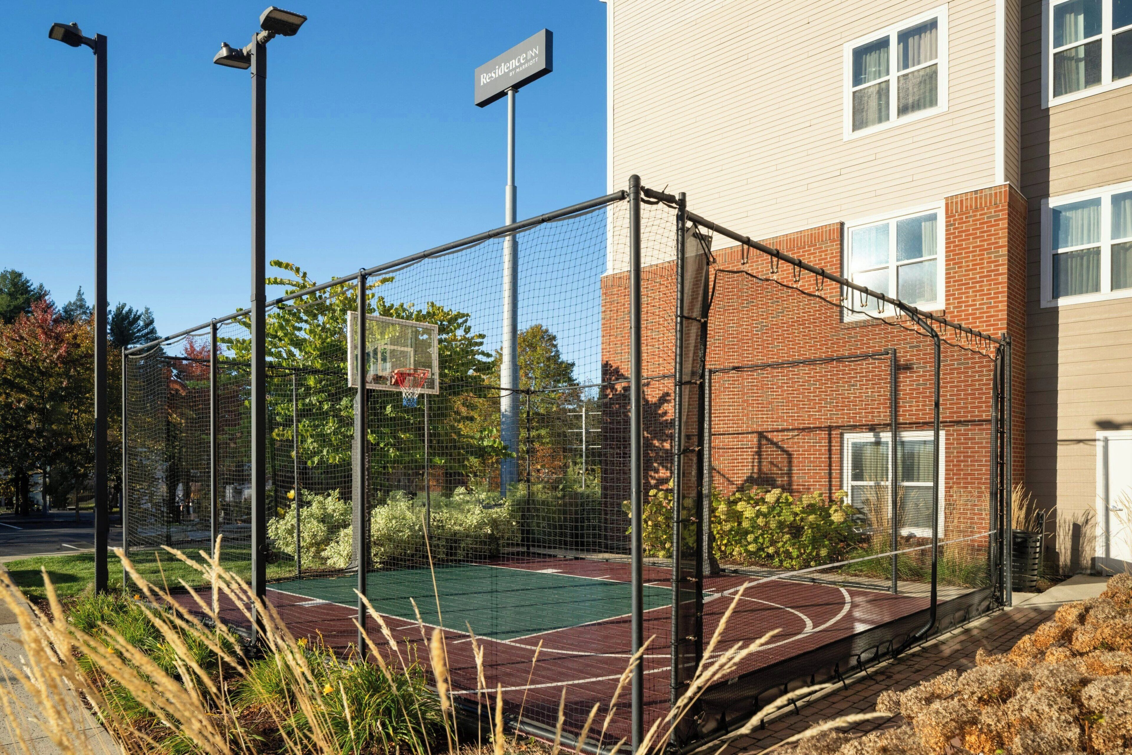 A basketball court enclosed by a fence, with a sign reading "Residence Inn."