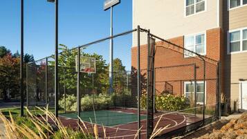 A basketball court enclosed by a fence, with a sign reading "Residence Inn."