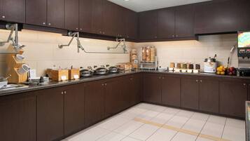 A modern kitchen with dark wooden cabinets, stainless steel appliances, and a variety of food items on the counter.