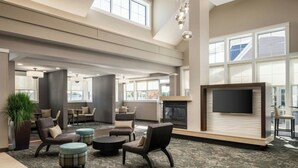A spacious lobby with comfortable seating, a fireplace, and large windows. - Residence Inn Springfield Chicopee (Chicopee)