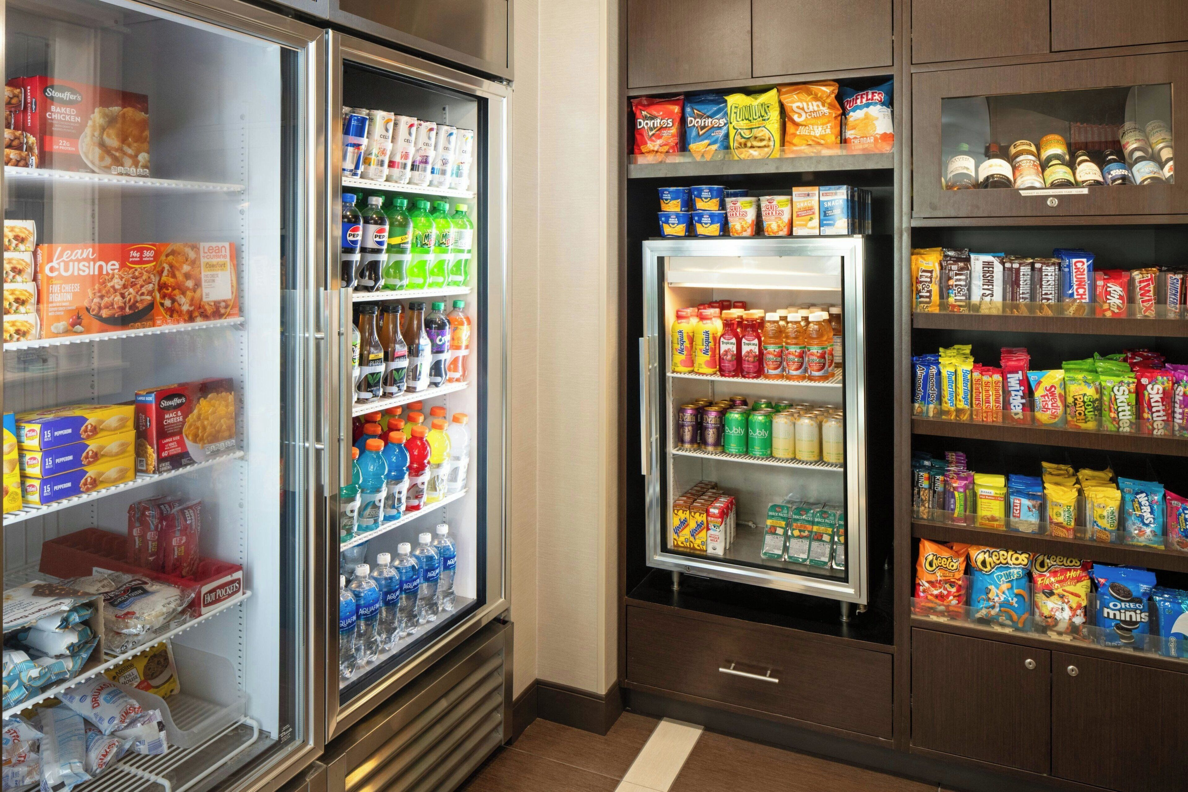 A refrigerated display case stocked with various food items and beverages, including snacks, dairy products, and bottled drinks.