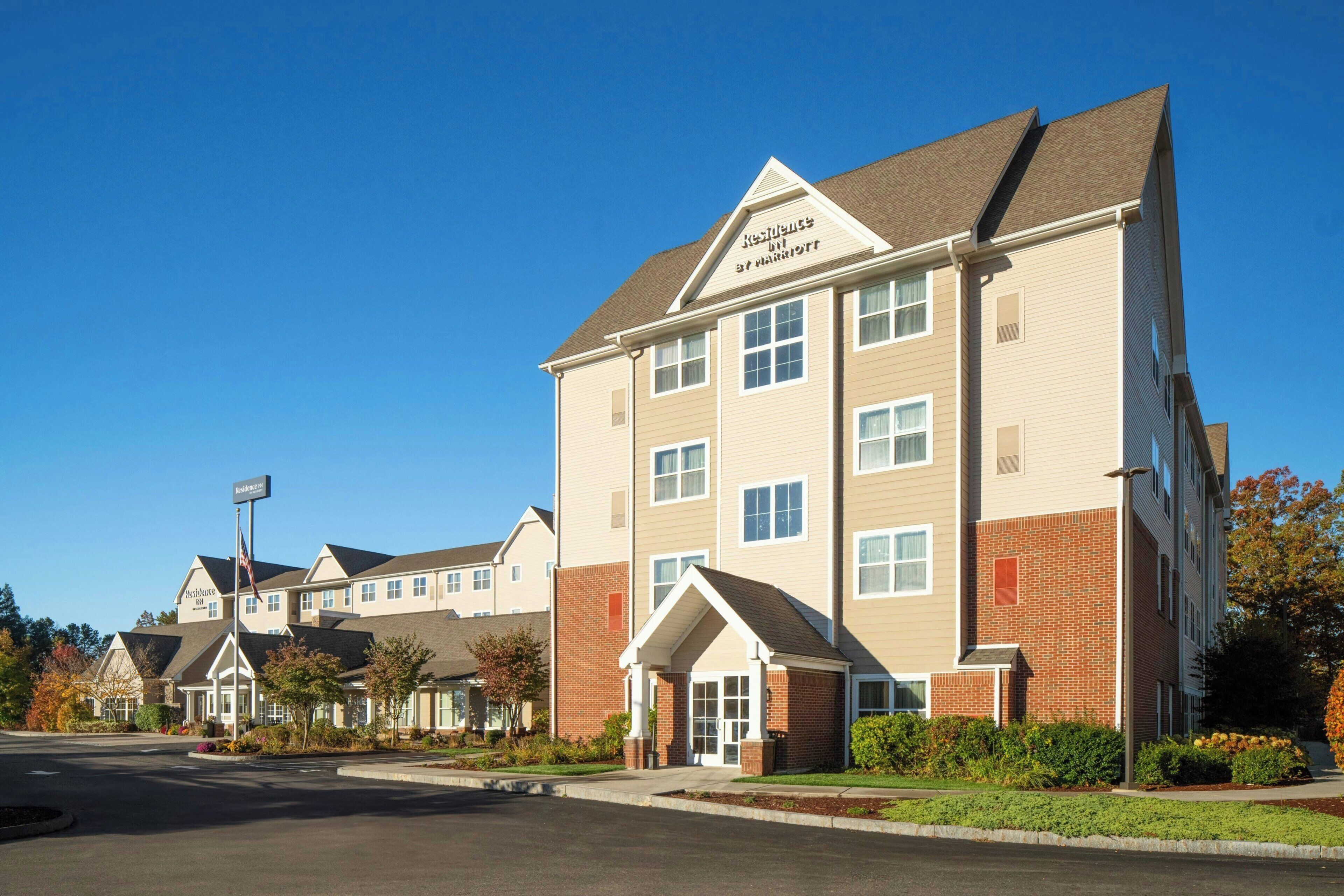 A multi-story hotel with a prominent entrance, a flagpole, and a clear blue sky.
