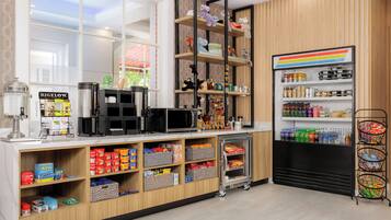 A modern kitchen with a coffee machine, microwave, and various food items on shelves.