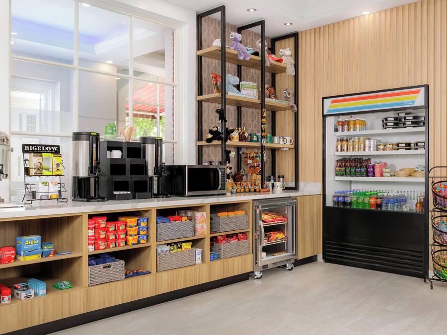 A modern kitchen with a coffee machine, microwave, and various food items on shelves.