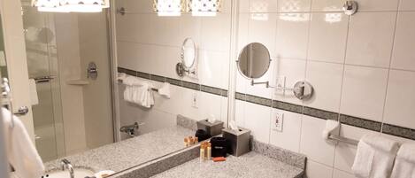 Un baño con un espejo grande, dos lavamanos y una ducha.