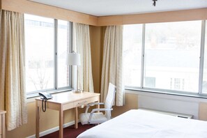 Enjoy a city view from the large window, with a comfortable bed, desk, and chair.