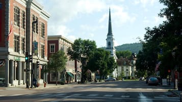 A street view with a church steeple, buildings with American flags, and a crosswalk.